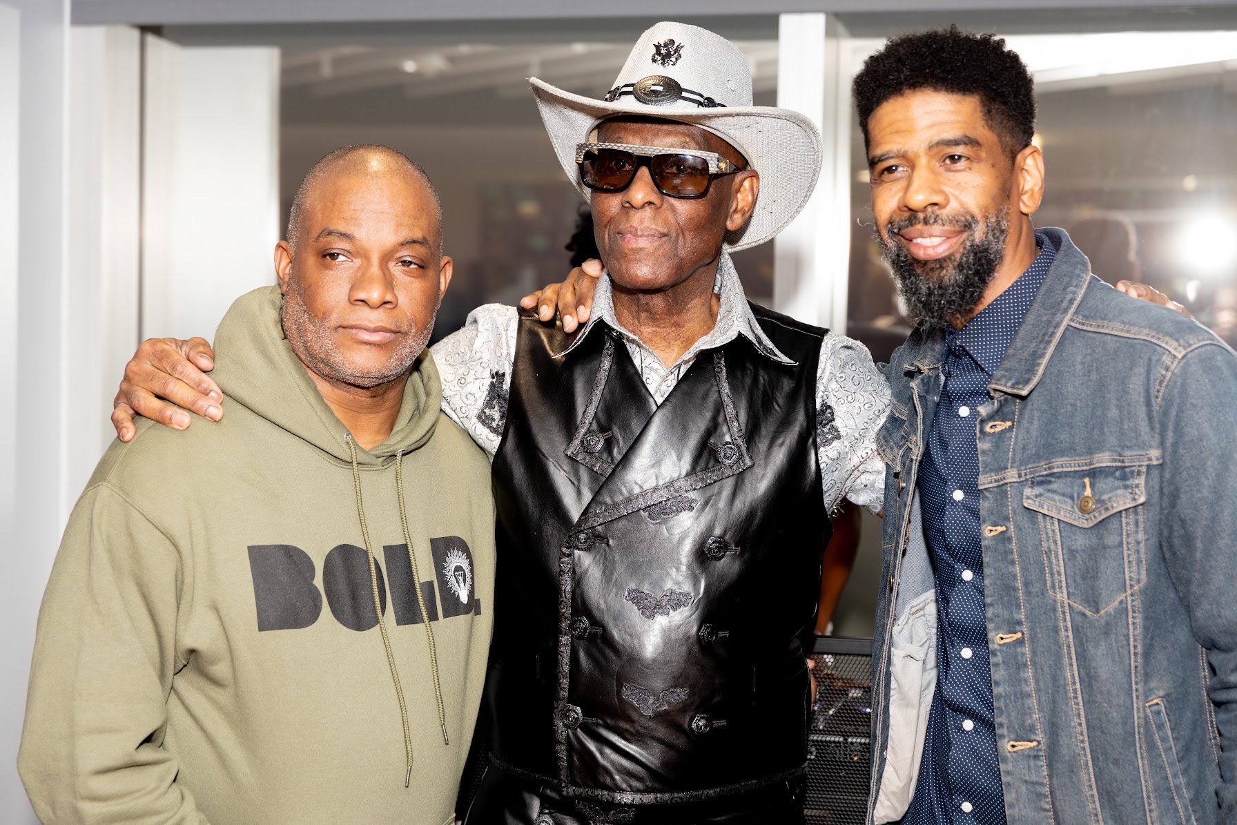 Mo and Troy arm in arm with a guest in a white cowboy hat and Western vest
